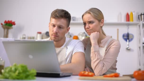 Pareja molesta leyendo recetas de comida en Internet, teniendo problemas con la cocina — Vídeo de stock