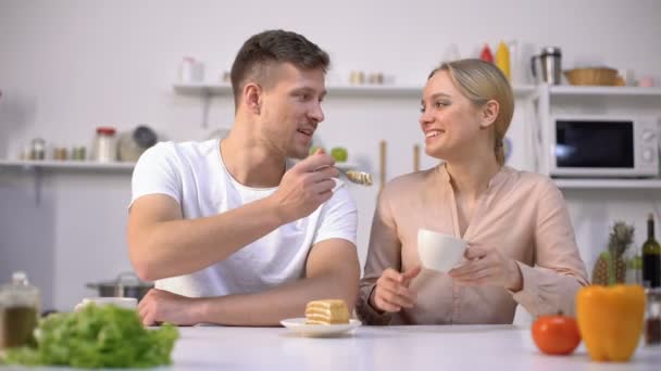 Bonito homem alimentando namorada com bolo, encontro na cozinha, atmosfera romântica — Vídeo de Stock