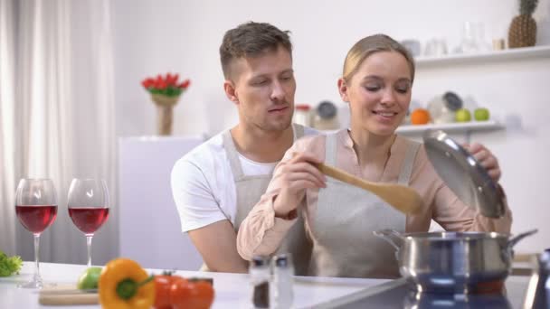 Boldog pár főzés együtt a konyhában, női kóstoló leves, egészséges étel — Stock videók