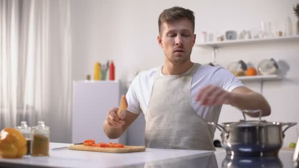 Pohledný mladý muž ochutnávka zeleninové polévky, vaření zdravých vegetariánských jídel — Stock video