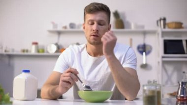 Üzgün tek adam kahvaltı için tatsız tahıllar yemek, iştahsızlık