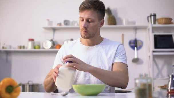 Knappe mannelijke eten maïsvlokken met melk, voedend en gezond ontbijt — Stockvideo