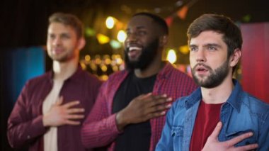 Multiracial arkadaşlar futbol oyunu başlamadan önce milli marşı şarkı, pub
