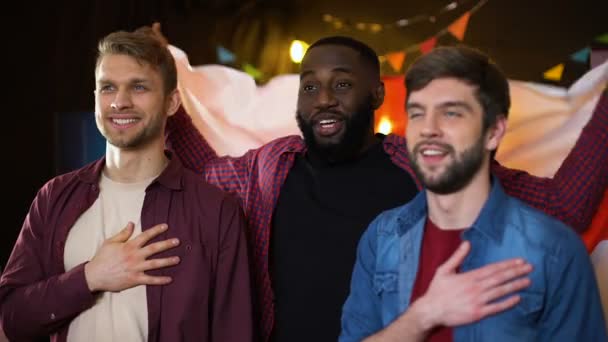Caucasian and black male friends singing national anthem, waving english flag — Stock Video