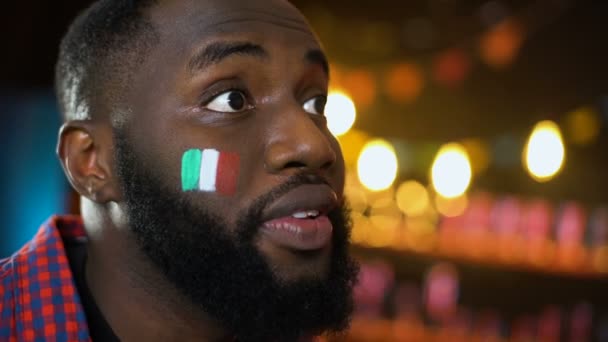 Anxious black soccer fan with italian flag painted on cheek making facepalm loss — Stock Video