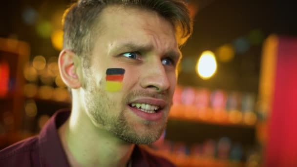 Teleurgesteld mannelijke fan met Duitse vlag geschilderd op Wang zwaaiende hand, falen — Stockvideo