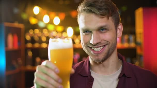 Lachende man geproost bier glazen met vriend, genieten van resultaten tijd in pub — Stockvideo