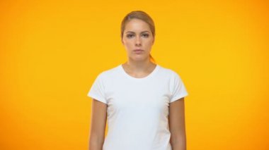 Turuncu arka plan üzerinde duran çene üzerinde el ile Düşünceli kadın, tereddüt