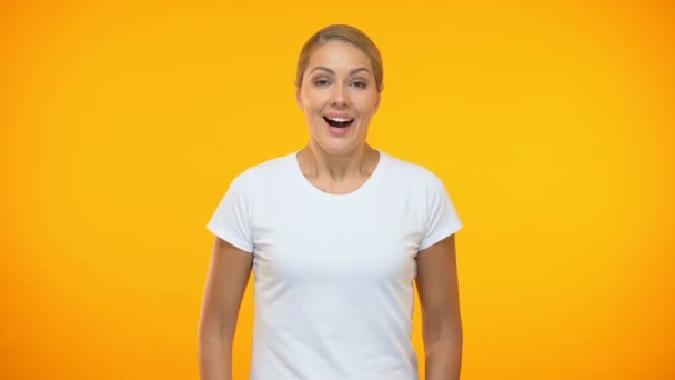 オレンジ色の背景に驚いた若い女性、良いニュース驚き、幸せ — ストック動画