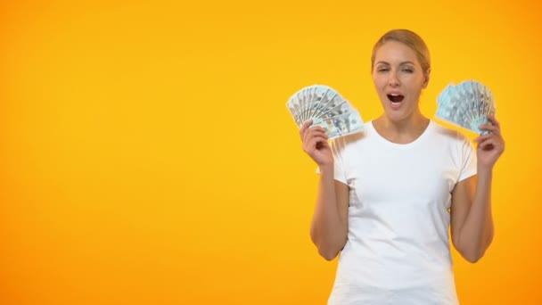 Mujer emocionada mostrando billetes de dólar sobre fondo naranja, ganar la lotería, ingresos — Vídeos de Stock