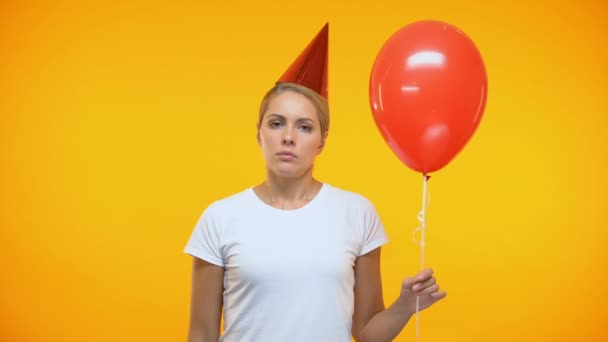 Sad adult woman blowing noisemaker holding balloon, bad mood at birthday party — Stock Video