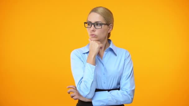 Thoughtful woman looking right and left on orange background, difficult choice — Stock Video