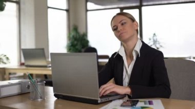 Dizüstü bilgisayarda çalışırken boyun ağrısı çeken çalışan, ofiste stresli bir gün
