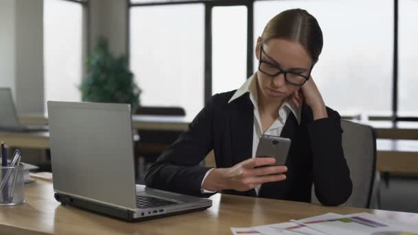Kvinne som sjekker sosiale medier på telefonen, distrahert fra jobben, produktivitetskonseptet – stockvideo