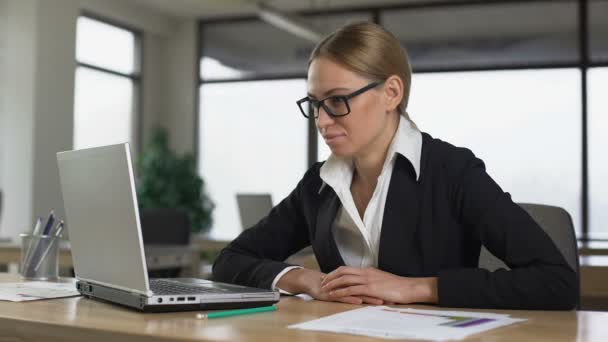 Γυναίκα χασμουριέται ενώ διαβάζει στο laptop, κουρασμένος από μονότονη εργασία στο γραφείο — Αρχείο Βίντεο