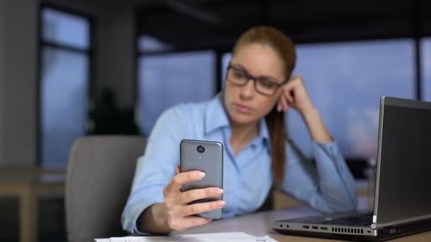 Ленивая женщина использует телефон вместо того, чтобы делать работу на компьютере, непродуктивность концепции — стоковое видео