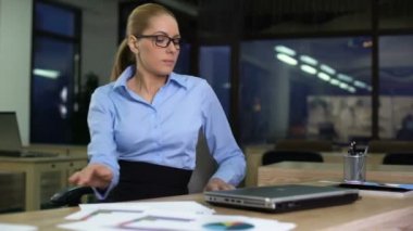 Woman opening laptop to start night shift, motivated employee working overtime