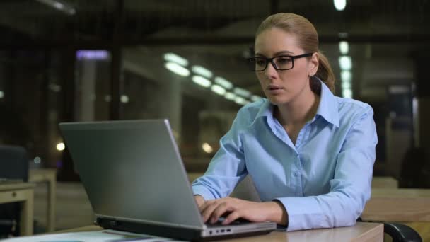 Уставшая женщина проверяет время дежурства, работает сверхурочно в офисе, чтобы уложиться в срок — стоковое видео