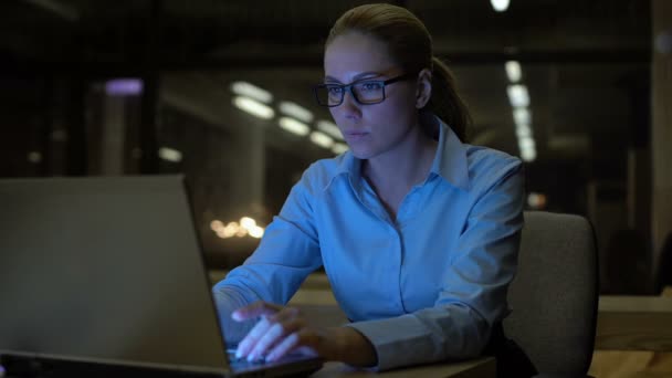 Hübsche Frau, die spät abends im Büro am Laptop arbeitet, gewissenhafte Angestellte — Stockvideo