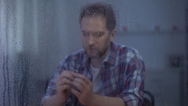 Hombre molesto sosteniendo anillo de compromiso en el día lluvioso, concepto de divorcio, conflicto familiar — Vídeo de stock