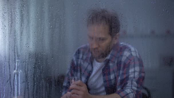 Álcool viciado homem bebendo vodka na solidão atrás de janela chuvosa, problemas — Vídeo de Stock