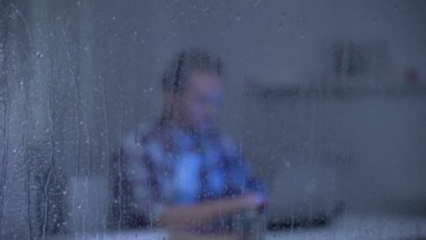Συγκεντρωμένος άνθρωπος που εργάζεται στο σπίτι πίσω από βροχερό παράθυρο, ανεξάρτητος — Αρχείο Βίντεο