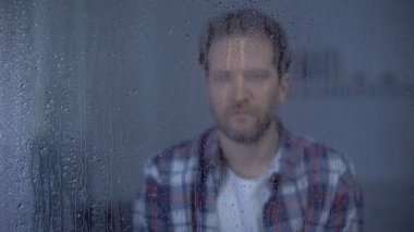 Wife putting hand on shoulder of depressed husband, family support, rainy day