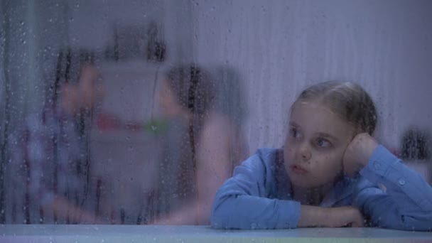 Upset girl sitting behind rainy window, listening parents quarrel, problems — Stock Video