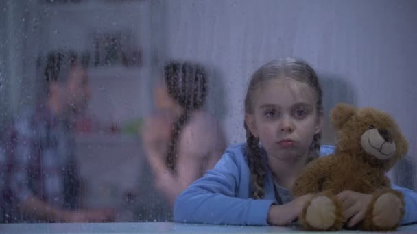 Rémült lány ölelgetés mackó esős napon, hallás szülők veszekedés — Stock videók