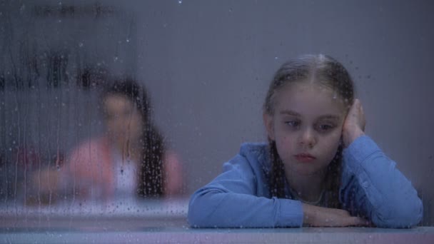 Triste petite fille assise le jour de pluie, mère dépendante buvant de l'alcool dans la chambre — Video