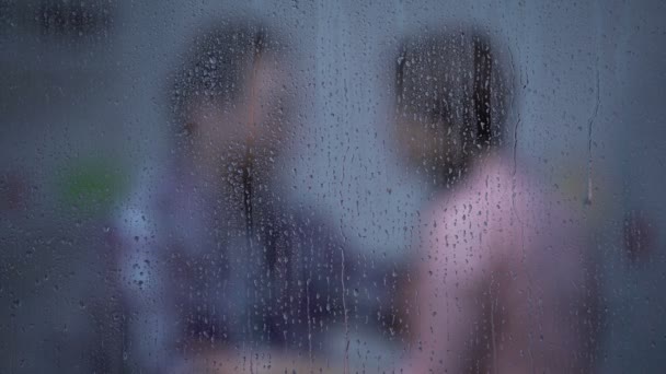 Мужчина и женщина обнимаются в комнате в дождливый день, примирение после ссоры — стоковое видео