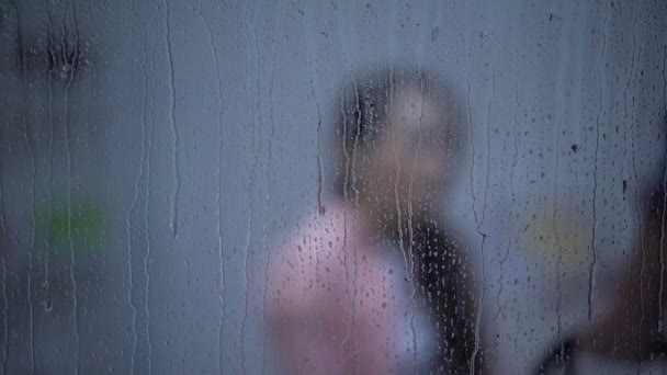 Испуганная женщина защищает от агрессивного мужа с поясом, дождливый день — стоковое видео