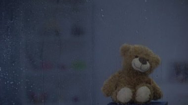 Gök gürültüsü hava, umut ve destek yağmurlu pencere arkasında eşik üzerinde Teddy ayı