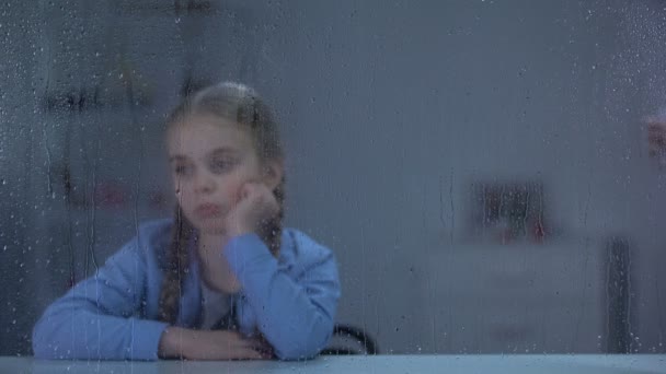Sjuksköterska föra vatten och piller till sjuk liten flicka tittar genom regniga fönster — Stockvideo