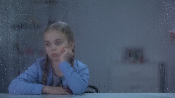 Nurse bringing water and pills to sick little girl looking through rainy window — Stock Video