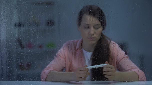 Zdenerwowany kobieta trzymając test ciążowy z wynikiem ujemnym, Niepłodność, deszczowy dzień — Wideo stockowe