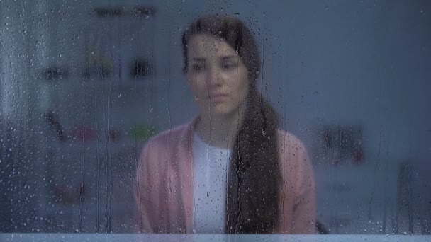 Husband putting hands on wifes shoulder behind rainy window, family support — Stock Video