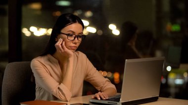 Sıkılmış kadın dizüstü bilgisayar üzerinde çalışan, fazla mesai ile yorgun, motivasyon eksikliği