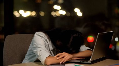 Yorgun genç bayan masada uyuyor, ofiste sıkılmış hissediyor, iş yorgunluğu