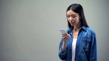 Akıllı telefonda gülümseyen kadın okuma mesajı, gri arka planda izole