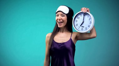 Pijama ve göz maskesi tutan saat neşeli kadın, iyi uyku koşulları