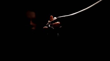 Karanlıkta sunan elden sigara alan kişi, nikotin bağımlılığı