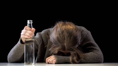 Drunk addicted female holding vodka bottle sitting table, problem hopelessness clipart