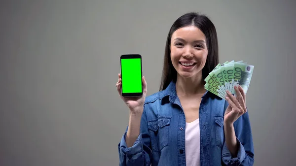 スマートフォンとユーロを持つ笑顔のアジアの女性 オンラインで働く キャッシュバック — ストック写真