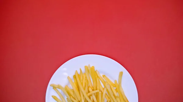 赤の背景にフライドポテトとホワイトプレート ファーストフードディナー — ストック写真