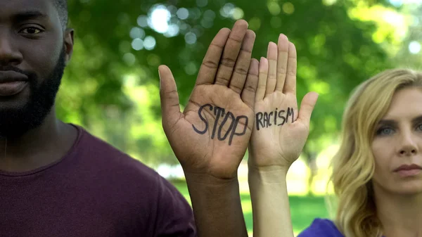 非洲裔美国人男子和高加索妇女显示手掌与停止种族主义短语 — 图库照片