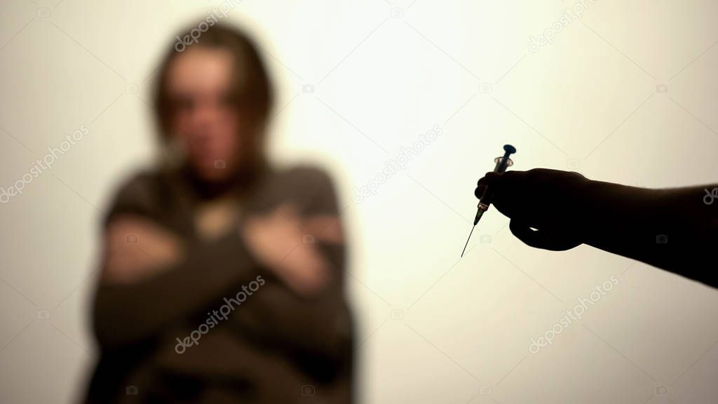 Drug dealer hand holding dose syringe on white background, rehab withdrawal