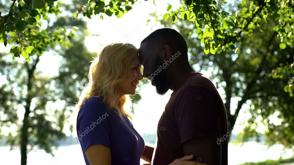 Loving mixed race couple looking at each other and nuzzling, tender feelings