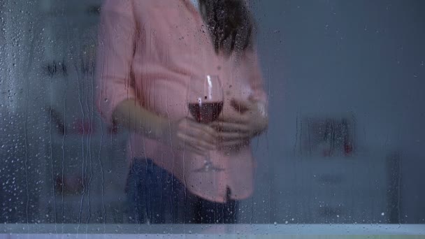 Έγκυος γυναίκα χαϊδεύοντας την κοιλιά και πίνοντας κρασί σε βροχερή ημέρα, ανεπιθύμητο μωρό — Αρχείο Βίντεο