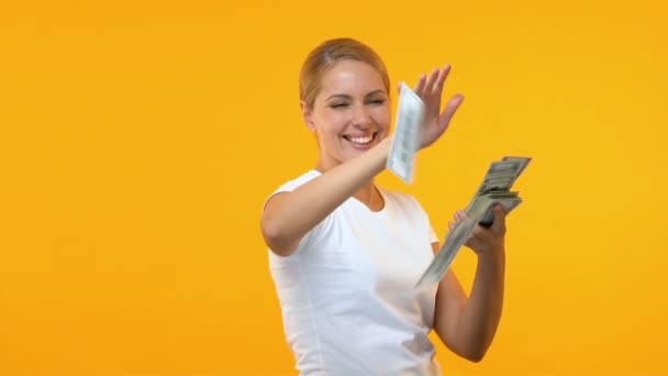 Εξαιρετικά ευτυχισμένη γυναίκα που πετάει δολάρια από πορτοκαλί φόντο, νικητής Λόττο — Αρχείο Βίντεο